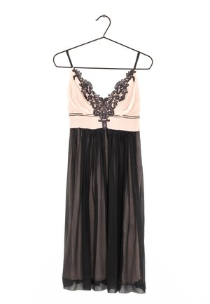 Vestido sin mangas con parte superior rosa maquillaje con detalles de encaje negro y escote pronunciado, combinado con una falda negra transparente y fluida.