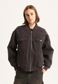 Dunkelbraune Bomberjacke aus Baumwollmischung, mit zwei Brusttaschen, Reißverschluss, gerippten Bündchen und einer glatten Textur.