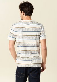 Puuvillane lühikeste varrukatega T-särk, millel on horisontaalsed triibud sinise, pruuni ja halli mustriga; standardne lõige ja ümar kaelus.