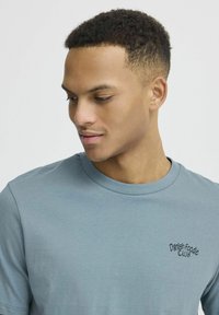 Lyseblå T-shirt med kortærmer lavet af bomuld, med rund halsudskæring og et sort broderet logo "Danish Foodie Club".