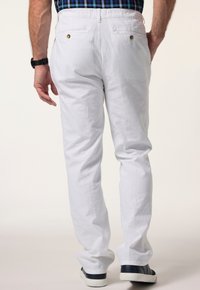 Vita linnebyxor med en avslappnad passform, som har två bakfickor, knappar i guldton och är kombinerade med marinblå sneakers.