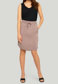 Světlounce růžová kolová sukně ke kolenům se stahovací šňůrkou v pase a bočními kapsami, doplněná černým tílkem a černými sandály.