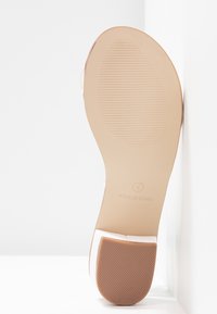 Semelle d'une chaussure beige avec talon texturé, taille 4, et inscription "Fabriqué en Chine" sur fond blanc.