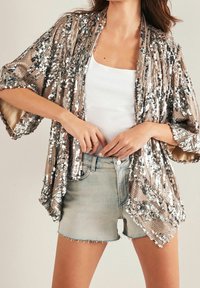 Cazadora kimono de lentejuelas en bronce, con un corte holgado, mangas cortas y un patrón brillante de lentejuelas plateadas y doradas sobre una base texturizada.