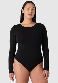 Mustan pitkähihainen bodysuit, joka on valmistettu venyvästä materiaalista, varustettuna pyöreällä kaula-aukolla ja korkeakatkaisulla lahkeella. Sileä pinta, minimalisti yksityiskohdissa.