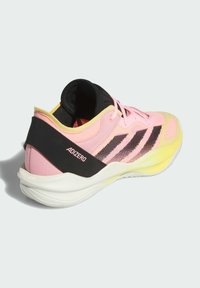 Adidas Adizero sko med en pink overdel, sorte accenter og en gul sål. Designet har en mesh tekstur og tre sorte striber på siden.