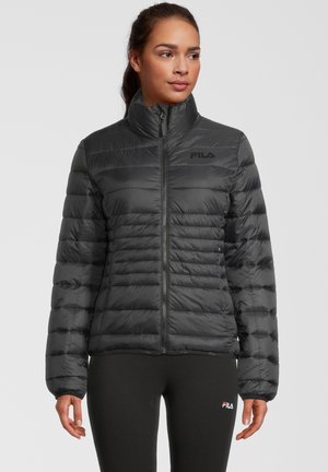 Zwarte pufferjack met een hoge kraag en ritssluiting, voorzien van een gewatteerd ontwerp en subtiele branding op de borst. Zachte textuur.