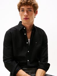 Camisa preta de botão, feita de um tecido suave, com colarinho clássico, botões brancos e um pequeno logotipo no peito.