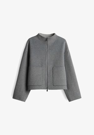 Giacca grigia con zip, dal taglio corto e squadrato, maniche lunghe e due grandi tasche quadrate sul davanti.