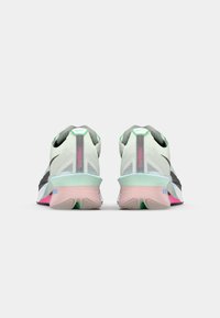 Running shoes with a mesh upper in light mint and grey, featuring a pink and green sole and reflective accents. Rounded toe design.