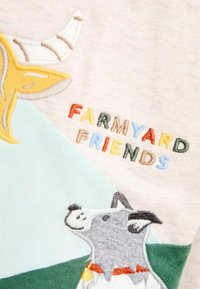 Broderad barnskjorta med en get och en hund, med texten "FARMYARD FRIENDS" i flerfärgade bokstäver. Mjuk bomullsblandning, pastellfärger.