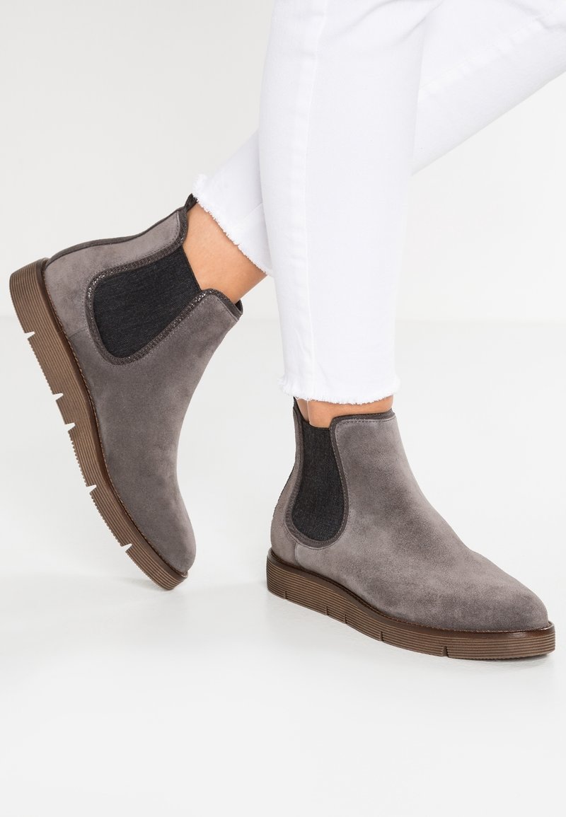 Bottines en daim gris avec panneaux latéraux élastiques et semelles en caoutchouc marron texturé. Bout arrondi et détails de couture minimalistes.