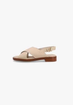 Sandalia de cuero beige con tiras cruzadas, correa ajustable en el talón con hebilla y tacón bajo de bloque de madera sobre fondo blanco.