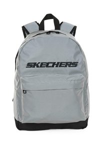 Mochila de tela gris con un gran bolsillo frontal, base negra y un destacado logotipo "SKECHERS" en negro. Correas de hombro acolchadas y asa superior.