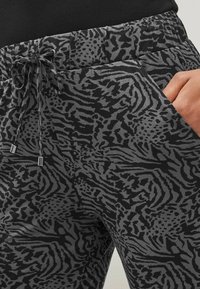 Zwarte en grijze joggers met een panterprintpatroon, voorzien van een elastische tailleband, trekkoordsluiting en zijzakken.