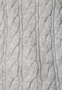 Suéter de punto gris claro con un patrón de trenzas que presenta cables elevados entrelazados y puntos texturizados en toda su superficie.