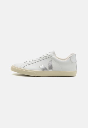 Baskets Veja blanches avec un logo argenté texturé, des lacets plats et une semelle en caoutchouc beige, un upper en cuir lisse et un design discret.