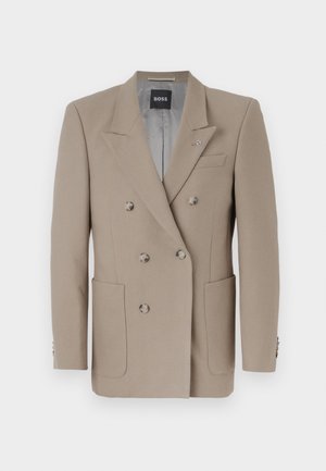 Blazer bege de dupla matelassagem com dois grandes bolsos frontais, lapelas afiadas e botões em tom de prata. Apresenta uma textura sólida e um ajuste elegante.