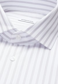 Camicia bianca da uomo con sottili righe grigie alternate, colletto classico e chiusura con bottoni. L'etichetta riporta la scritta "seidensticker".