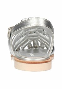 Srebrne metaliczne sandały o plecionym wzorze i płaskiej podeszwie. Posiadają gładką wewnętrzną wyściółkę i jasną drewnianą podeszwę.
