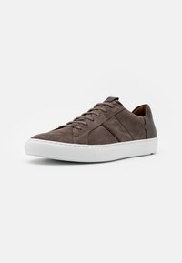 Sneaker in suede marrone con suole in gomma bianca, caratterizzate da una finitura liscia e un design essenziale con lacci. Accenti laterali sottili in marrone scuro.