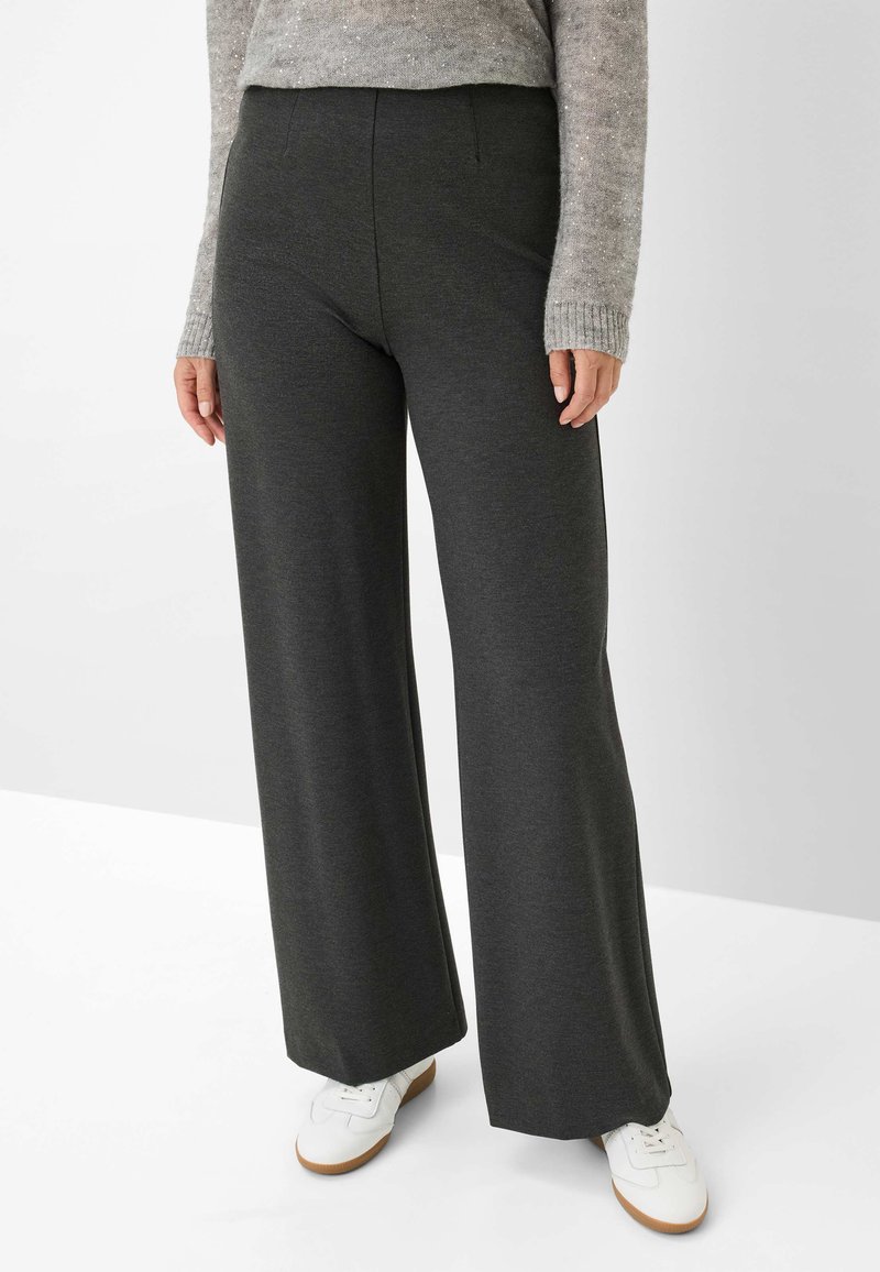 Hochtaillierte, weit geschnittene Hose aus dunkelgrauem Stoff. Mit Fronttaschen und einer glatten Textur. Kombiniert mit weißen Schuhen.