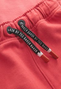 Koraalrode katoenen shorts met een elastische tailleband, uitgerust met zwarte trekkoorden met rode uiteinden en het merklabel "TED BAKER BAKER" erop.