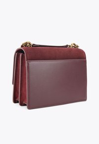 Sac en cuir bordeaux avec des accents en daim, forme rectangulaire, rabat repliable et quincaillerie en chaîne dorée. Surfaces lisses et texturées.