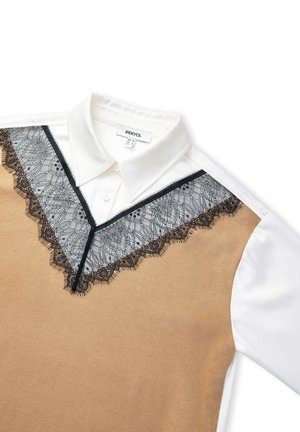 Pull beige avec bordure en dentelle noire et col blanc. La dentelle présente un motif floral. Étiquette visible au niveau du col avec le nom de la marque.