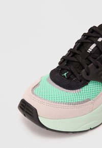 Sneaker mit einem mintgrünen Mesh-Obermaterial, schwarzen Wildlederakzenten und einer schmalen schwarzen Sohle, mit strukturierten Details und Schnürsenkeln.
