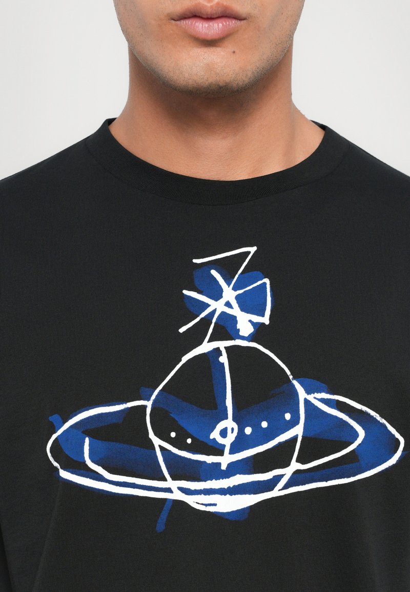T-shirt noir avec un design graphique abstrait bleu et blanc représentant une planète avec des anneaux, situé au centre sur le devant.