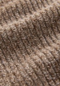 Brown knitted fabric with a textured ribbed pattern, exhibiting a soft, fuzzy surface and varying thickness throughout.