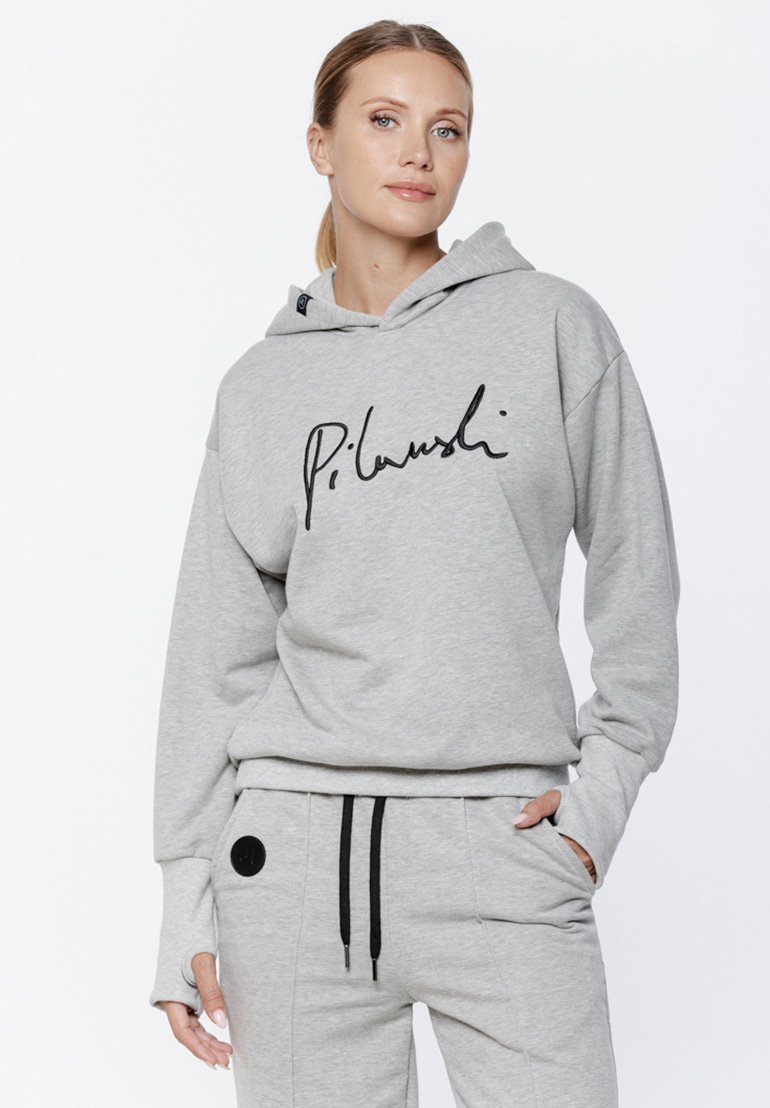 Szara bluza z kapturem z czarnym logotypem na przodzie, z kapturem na sznurki, luźnym krojem i ściągaczami na rękawach. Stworzona w zestawie z dopasowanymi szarymi dresami.