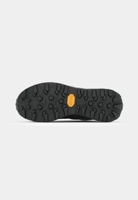 Semelle de chaussure de randonnée noire avec des motifs de crampons agressifs, marquage Vibram en orange, matériau en caoutchouc texturé, conçu pour l'adhérence et la durabilité.