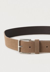 Καφέ σουέτ ζωνάκι με απαλό υφή, διαθέτοντας μεταλλική ασημένια αγκράφα και θηλιά για ρύθμιση, σχεδιασμένο με πολλά τρύπες.