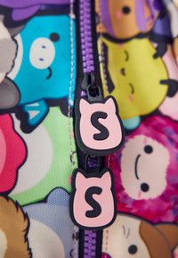 Bunt gemustertes Stoffmaterial mit Cartoonfiguren, lila Reißverschluss und pinkfarbenen, tierförmigen Zipper-Anhängern mit einem eingeprägten schwarzen Buchstaben 'S'.