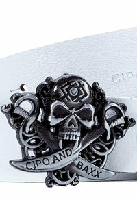 Ceinture en cuir blanc avec une boucle en argent en forme de crâne et de tibias, ornée de serpents entrelacés et d'une banderole sur laquelle est inscrite "CIPO AND BAXX."