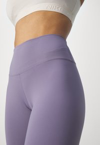 Högmidjade lila leggings i stretchigt material, med en mjuk yta och minimalistiska sömmar för en slimmad passform.