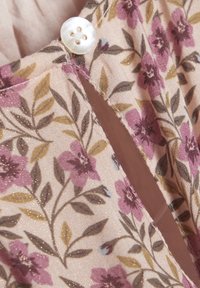 Látka s květinovým vzorem obsahující růžové květiny a zelené listy na světlém pozadí, doplněná bílým knoflíkem na výstřihu.