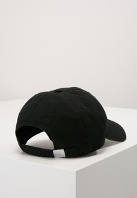 Gorra de béisbol de algodón negra con correa ajustable y un acento metálico plateado; logo en relieve en la parte posterior; visera curva.
