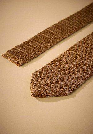 Brauner gestrickter Krawatte mit einem strukturierten Muster. Das schmale Ende hat eine einfarbige Ausführung mit einer spitz zulaufenden Spitze. Der Stoff wirkt flexibel und leicht.