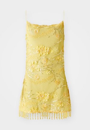 Vestido amarelo de alças com aplicações florais, lantejoulas e bainha com franjas de contas sobre um fundo branco.