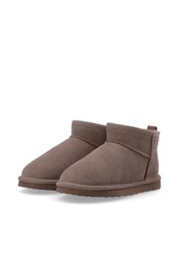 Stivali ankle in suede marrone con un gambale corto, punta arrotondata e semplici dettagli di cucitura. Suole in gomma piatta e un tassello di presa sul retro.