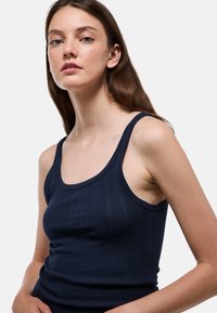 Débardeur bleu marine avec un col en U, présentant une texture côtelée et de fines rayures verticales. Confectionné dans un tissu doux et extensible.