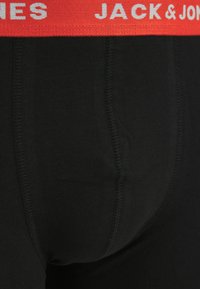 Boxer briefs neri in cotone elastico con un elastico rosso in vita che presenta il nome del marchio "JACK & JONES" in bianco. Cuciture visibili.