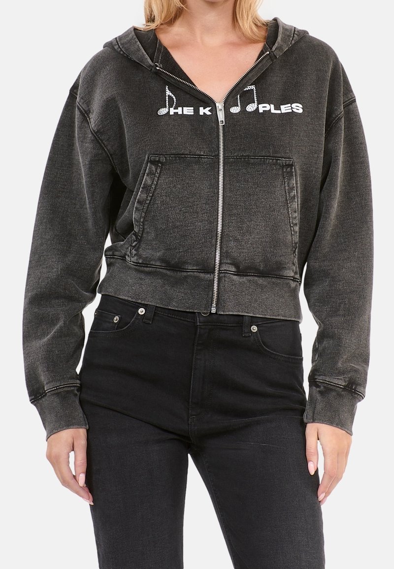 Zwarte denim hoodie met gerafelde randen, een ritssluiting aan de voorkant, twee zakken en een grafische tekst met muzieksymbool. Heeft een zachte textuur en een ontspannen pasvorm.