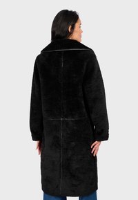 Cappotto in pelliccia sintetica nera con colletto alto e maniche lunghe. La parte posteriore presenta un semplice design a cucitura, che conferisce un aspetto morbido e strutturato.