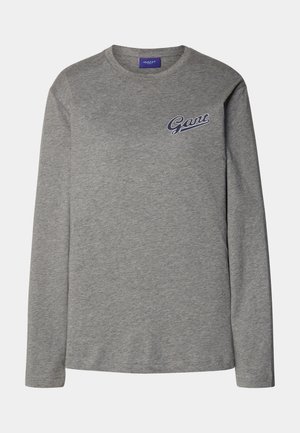 Harmaa pitkähihaisen pikeepaidan, jossa vasemmassa rinnassa pieni tummansininen "Gant"-logo ja sisäkauluksessa vastaavan sininen merkki.