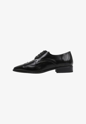 Chaussure de ville en cuir noir avec un bout pointu, perforations décoratives et un petit talon carré. Présente un système de laçage et une texture lisse.