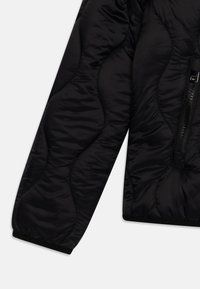 Giubbotto imbottito nero con design trapuntato, texture liscia, chiusura con zip e polsini elasticizzati per una vestibilità aderente.